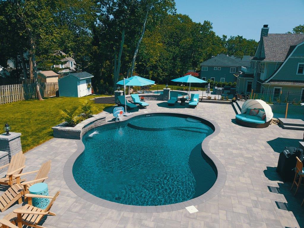 Custom freeform pool with paver deck and outdoor lounge area